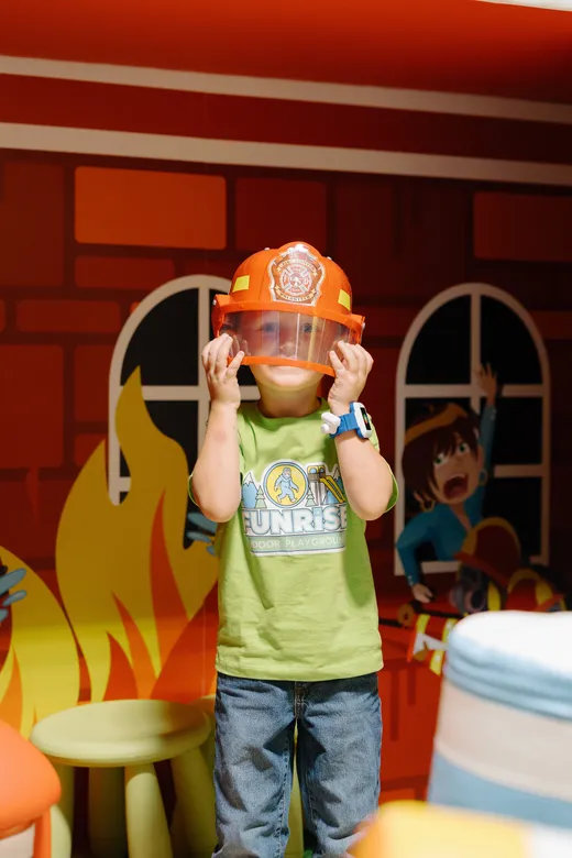 Preschooler in a fire helmet at the Funrise playhouse