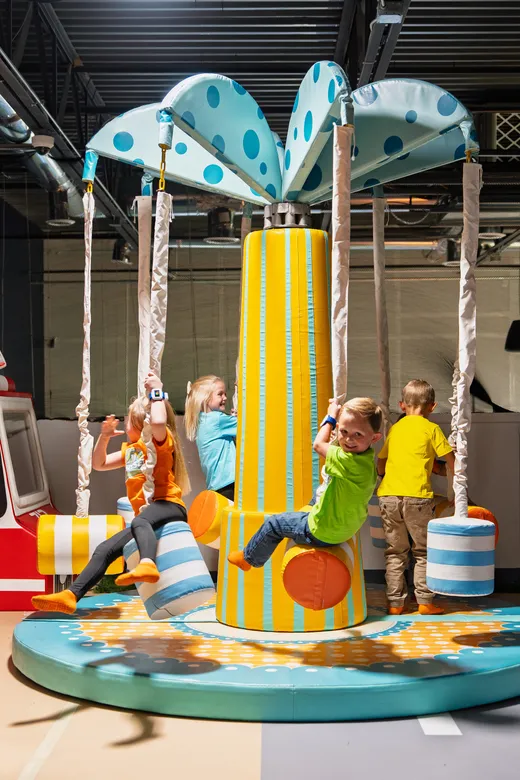 Young kids riding the spinning swing at the Funrise indoor playground